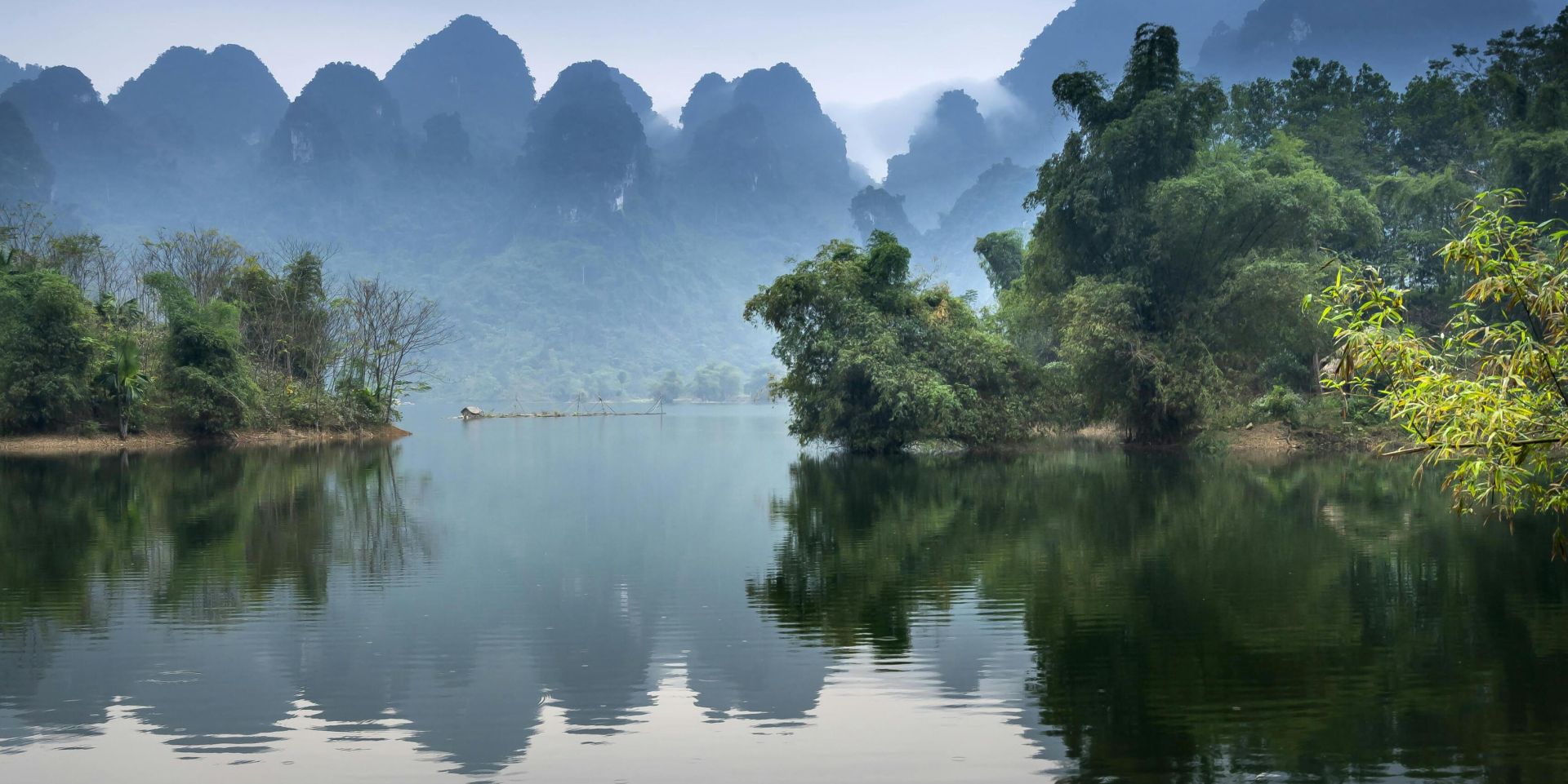 A tranquil river scene with a canoe, misty mountains, and lush greenery, perfect for nature lovers.