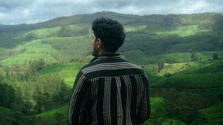 A man looking over the green hills of Munnar, Kerala. Perfect for themes of solitude and nature.