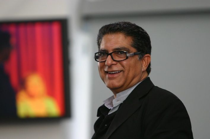 Speaker addressing large audience with phones lit up at night event.